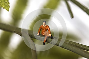 Tiny man sitting on a branch