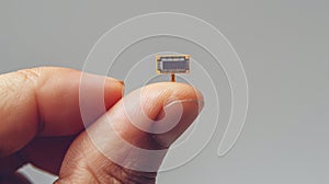 Tiny microchip on tip of human finger, on pale grey background. Copy space. Macro