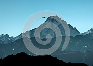 Tiny mountain climber scaling a snow covered hill being rescued by a rescue helicopter. Sky background with space for copy.