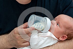 Tiny newborn baby eats milk formula from a bottle