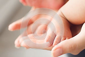 Tiny newborn baby foot in female hands, close-up