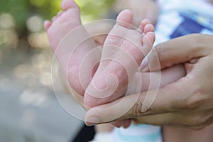 Tiny newborn baby foot in his mother`s palm in warm colors in soft focus background. Hands of mother and baby foot.