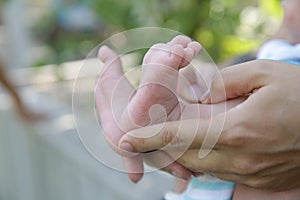 Tiny newborn baby foot in his mother`s palm in warm colors in soft focus background. Hands of mother and baby foot.