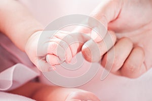 Tiny newborn baby hand holding mother finger with love