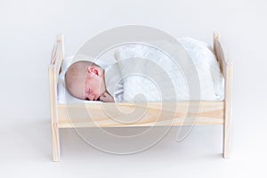 Tiny newborn baby sleeping in a toy crib