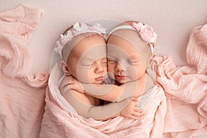 Tiny newborn twin girls. A newborn twins sleeps next to his sister.