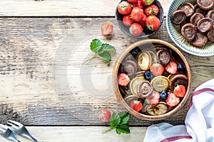 Tiny pancake cereal and chocolate mini pancakes in a wooden bowl with honey and strawberries on a wooden background. Top view.