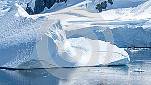 Tiny Penguins on Ice Floe and on Huge Iceberg with Fissure in Antarctica near Petermann Island