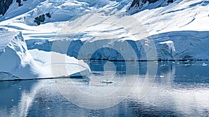 Tiny Penguins on Ice Floe and on Huge Iceberg with Fissure in Antarctica near Petermann Island