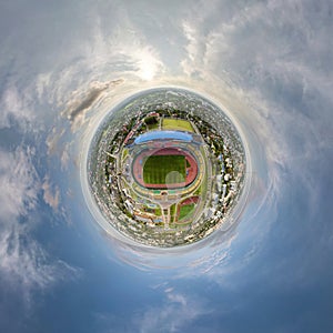 tiny planet in sky with clouds overlooking above on empty stadium or sports complex. Transformation of spherical 360 panorama in