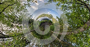 Tiny planet Transformation with curvature of space. Abstract torsion and spinning of full flyby panorama in forest near lake