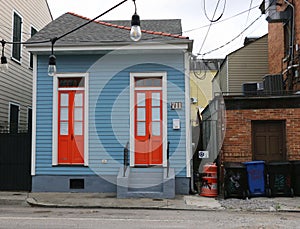 Tiny, quaint blue Creole cottage with bright orange doors , New Orleans.