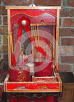 Tiny red Buddhist altar with incense sticks photo