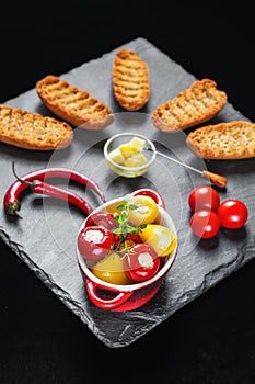 Tiny red and yellow hot peppers filled with cheese Balkan delicacy served with rusk, chilli peppers and cherry tomatoes photo