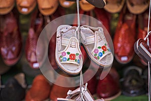 Tiny sandals with colorful flowers hanging from a string for sale at Olvera Street in Los Angeles California