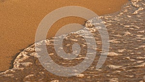 Tiny sea wave over sand, small bubbles of water