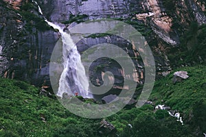 Tiny traveler figure near the Yogini waterfall in Indian Himalaya