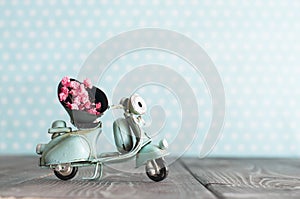 Tiny vintage toy blue motorcycle with bunch of pink flowers