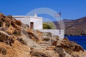 Tiny white church with greek flag on Tinos Island