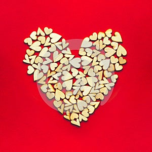 Tiny wooden hearts in the shape of a heart on red background