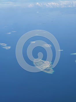 Tinyy archipelago islands in the middle of ocean, pictured from jetplane