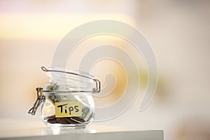 Tip jar with money on table against blurred background, space for text