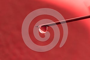 On the tip of a needle from a syringe drop of liquid