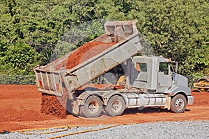 Tip truck dumping dirt on a construction site