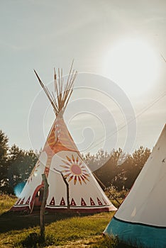 Tipi house in the forest against the background of trees, camping, village in the forest, camping. Indian teepee house at sunset