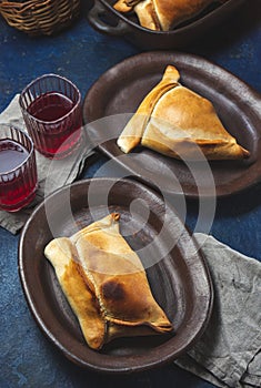 Tipical Chilean baked empanadas de pino y napolitano on clay plates with wine. Dish and drink on 18 September party