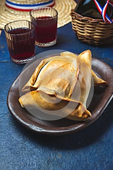 Tipical Chilean baked empanadas de pino y napolitano on clay plates with wine. Dish and drink on 18 September party