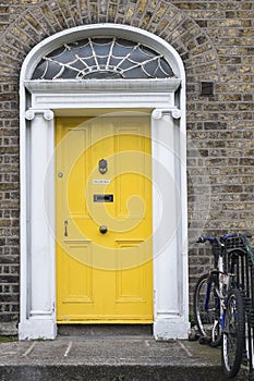 A tipical yellow wooden door in Dublin of a victorian house with bycicle photo