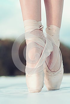 On the tips of the toes. Female feet in pointe shoes. Pointe shoes worn by ballet dancer. Ballerina shoes. Legs in white