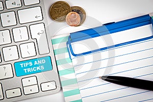 Tips And Tricks. Computer keyboard on a white office desk with various items