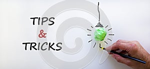 Tips and tricks symbol. Businessman writing words `Tips and tricks`, isolated on beautiful white background. Light bulb icon. photo