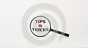 Tips and tricks symbol. Magnifying glass with words `Tips and tricks`. Beautiful white background. Business, tips and tricks