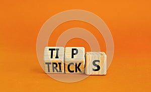 Tips and tricks symbol. Turned wooden cubes and changed the word tricks to tips. Beautiful orange table, orange background.