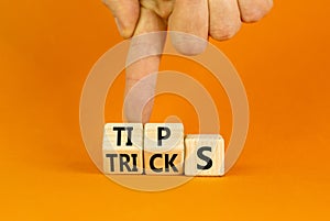 Tips and tricks symbol. Turned wooden cubes and changed the word tricks to tips. Beautiful orange table, orange background.