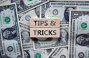 Tips and tricks symbol. Wooden blocks with words `Tips and tricks`. Beautiful background from dollar bills. Business, tips and