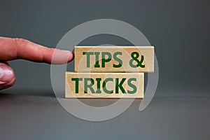 Tips and tricks symbol. Wooden blocks with words `Tips and tricks`. Beautiful grey background. businessman hand. Business, tips