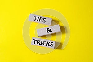 Tips and tricks symbol. Wooden blocks with words Tips and tricks. Beautiful yellow background. Business concept and Tips and