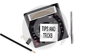 TIPS AND TRICKS text on sticker on calculator with pen,pencil on the white background