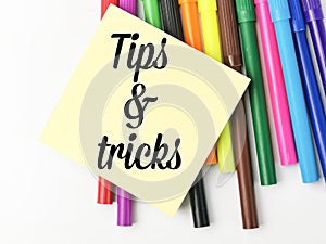 Tips and tricks written on yellow paper note with colorful pen.