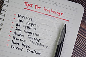 Tips For Wellbeings write on a book isolated on Wooden Table
