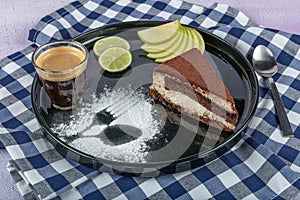 Tiramisu cake and coffee. Stylish Italian dessert with a piece of Tiramisu cake on a black plate and a cup of black coffee, served