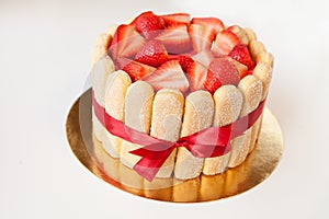 tiramisu cake with strawberries, ladyfingers, mascarpone and red bow-tape isolated on white
