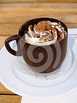 Tiramisu chocolate cup on a white plate served on a wooden table