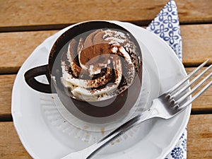 Tiramisu chocolate cup on a white plate served on a wooden table