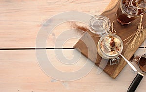 Tiramisu with a cup of iced coffee, top view on wooden board