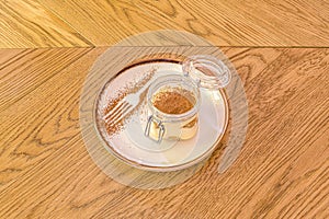 Tiramisu dessert mounted in a watertight decorative container with decorative sprinkled cocoa